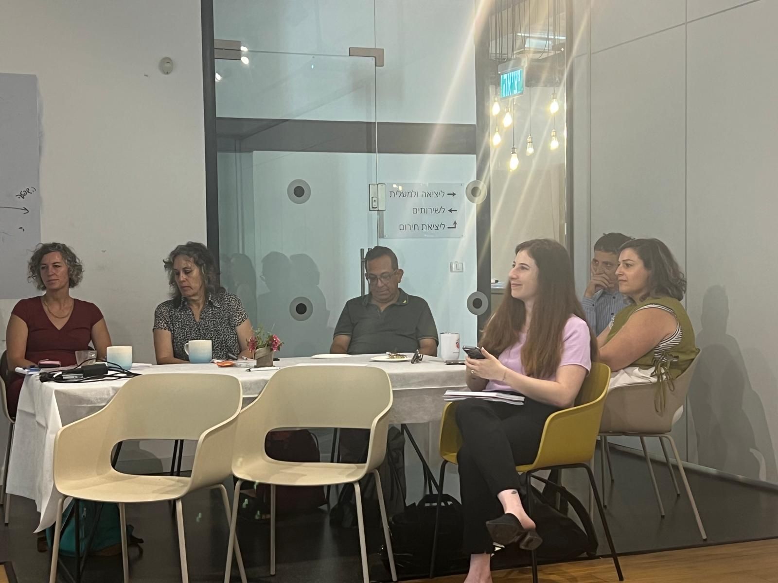 Group of people sitting around a table listening to a presentation in a conference room.