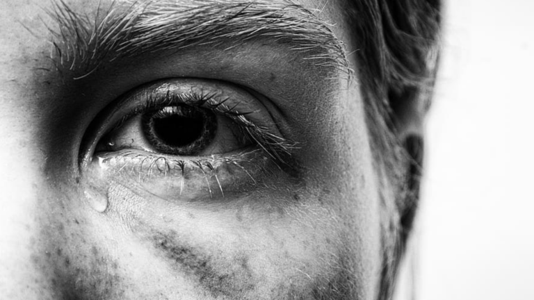 A close up of a woman's eye with a tear in the corner.