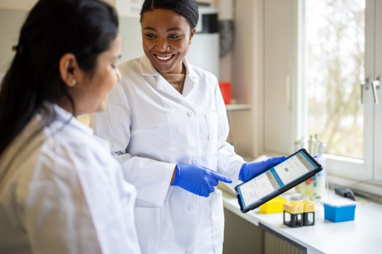 Image of 2 women in a lab looking at a tablet.
