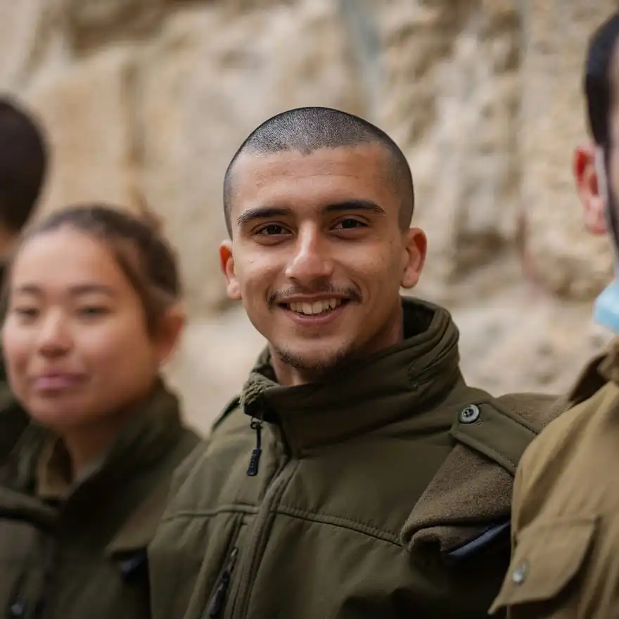 Close-up of a smiling young man in military uniform with colleagues